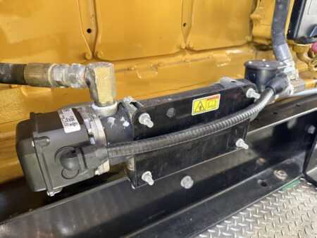 Hotstart coolant heater assembly mounted on Caterpillar engine.