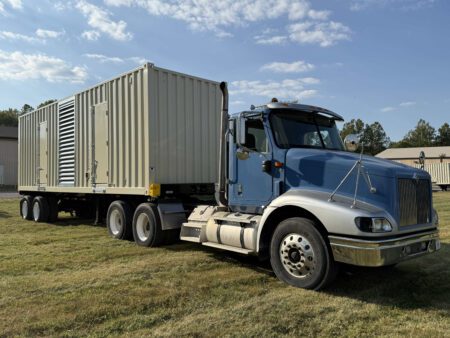 Rear-left angle of containerized CAT C27 generator on trailer.