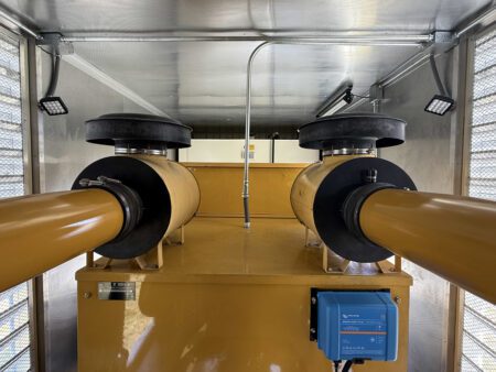 Dual exhaust discharge system inside containerized generator.