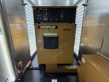 Containerized generator enclosure front view with Caterpillar control panel.