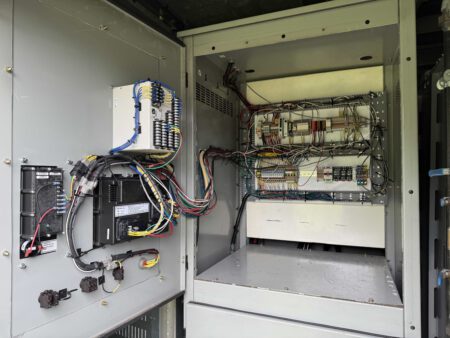 Open Caterpillar generator control cabinet showing wiring harnesses, relays, and control modules.