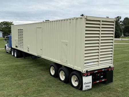 Caterpillar generator container on trailer, front-right angle.