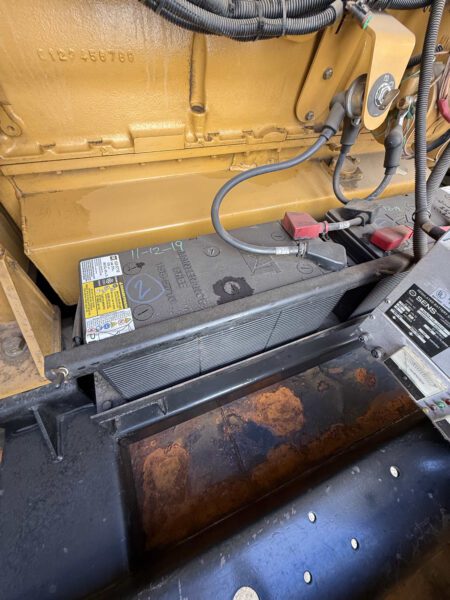 Starting battery bank and tray inside 2000 CAT 3412 500kW generator (S/N BPG00168) with cables; surface rust visible on base pan.