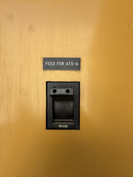 Close-up of output breaker handle labeled “FEED FOR ATS-A” inside 2000 CAT 3412 500 kW generator; small tag shows 800A.