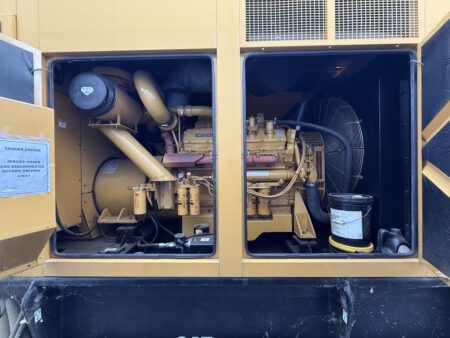 Engine compartment with both access bays open on 2000 CAT 3412 500 kW generator showing air intake canister, dual filters, engine, and large cooling fan (S/N BPG00168).