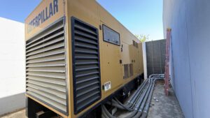 Exterior of 2000 Caterpillar 3412 500 kW generator—sound-attenuated enclosure with louvered end and conduit runs (S/N BPG00168).