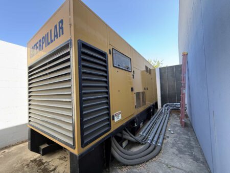 Exterior of 2000 Caterpillar 3412 500 kW generator—sound-attenuated enclosure with louvered end and conduit runs (S/N BPG00168).