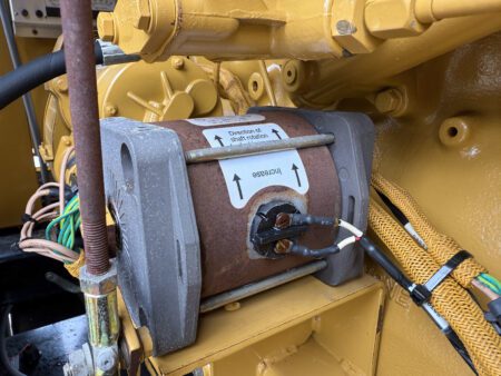 Close-up of the engine governor actuator on a 2003 Caterpillar 3306 250kW generator, showing wiring connections and adjustment markings.