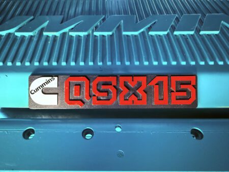Cummins QSX15 red and black engine badge mounted on the engine cover.