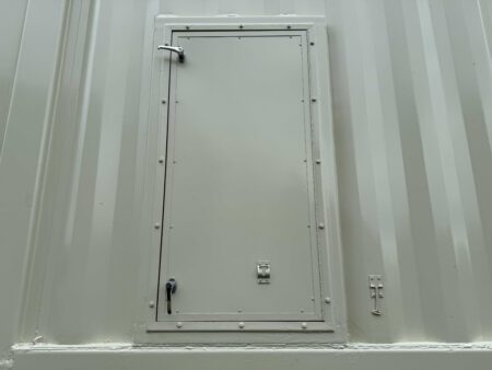 Closed personnel access door on Caterpillar 3516C generator enclosure with heavy-duty hinges and latch system.