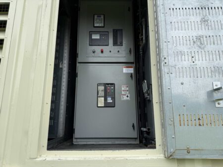 Side access door open showing generator circuit breaker and control distribution section inside Caterpillar 3516C containerized generator.