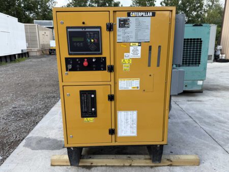 Caterpillar generator control panel with digital display, emergency stop, and breaker switches.