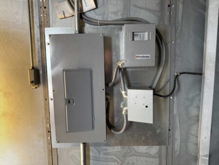 Wall-mounted breaker panel with SENS EnerGenius battery charger and junction box