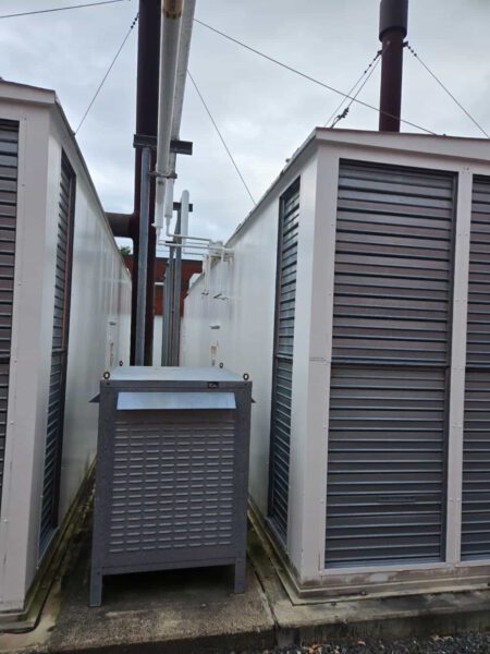 Rear view of CAT generator enclosure with louvered ventilation panels and exhaust stack.