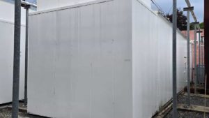 Front view of Caterpillar generator enclosure with exhaust stack and top-mounted silencer.