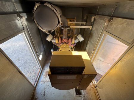 Inside Caterpillar generator enclosure showing engine and exhaust silencer