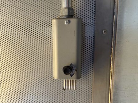 Wall-mounted thermostat inside generator enclosure with adjustable dial